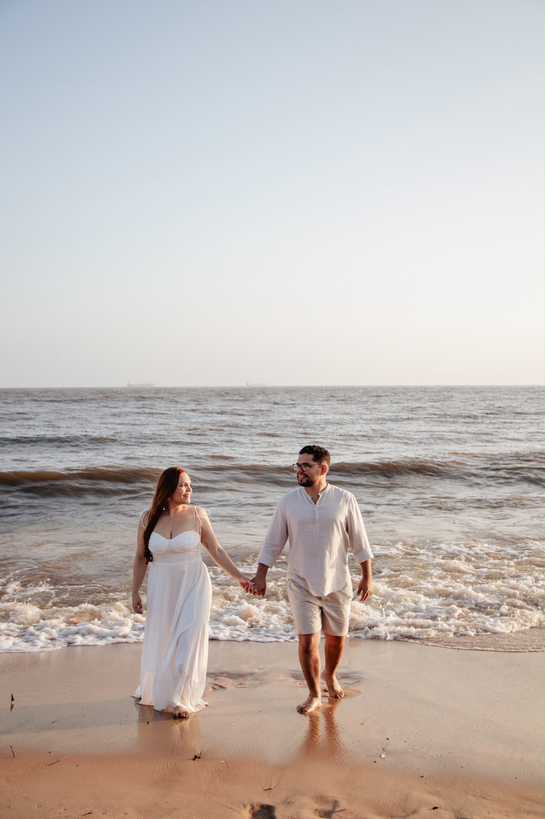 Aline e Artur caminhando na beira do mar